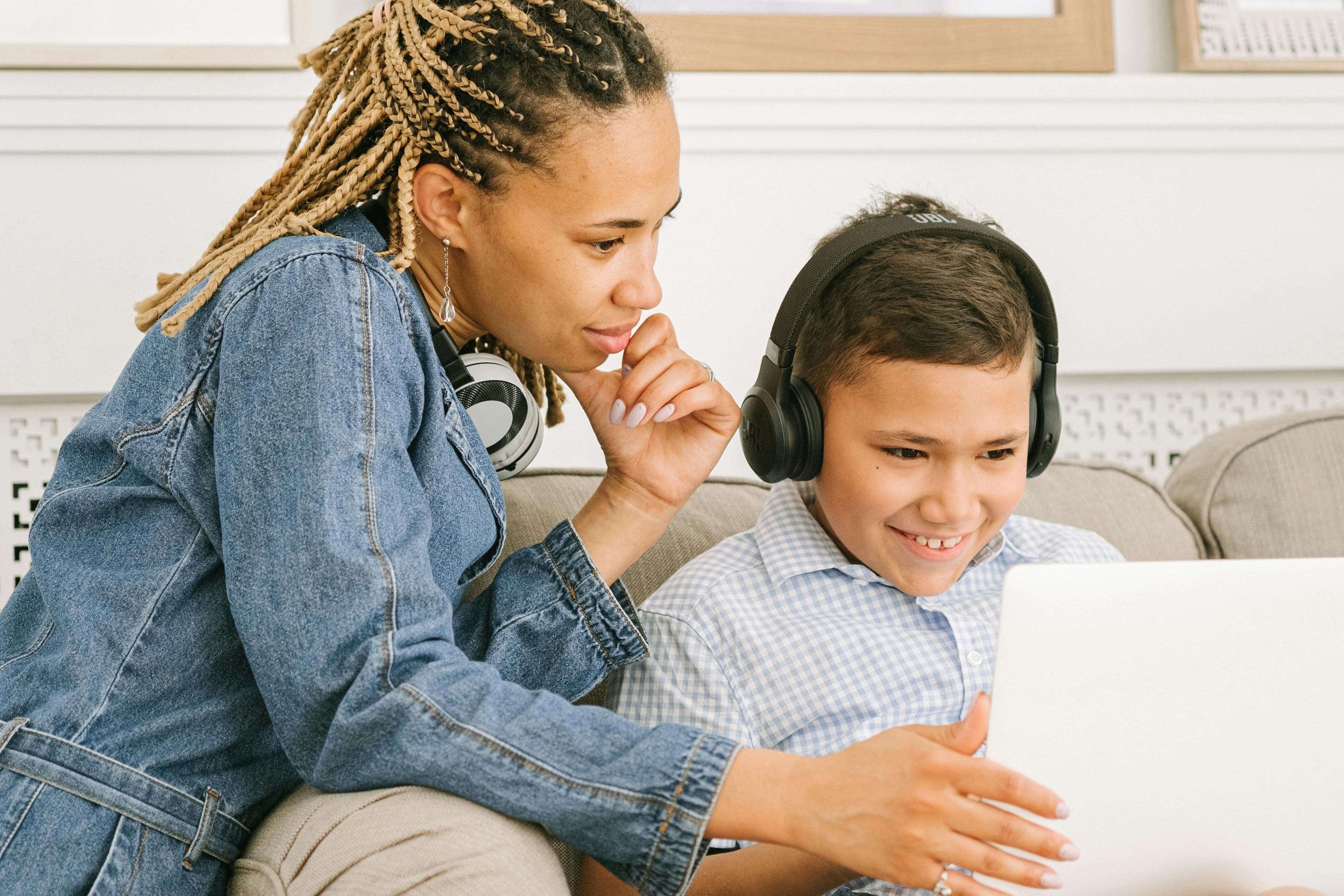 Woman in Blue Denim Jacket with Son wearing headphones Holding White Laptop